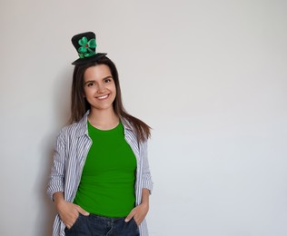 Image of St. Patrick's day party. Pretty woman in green leprechaun hat on light grey background. Space for text