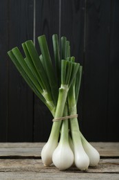 Photo of Bunch of fresh green spring onions on wooden table