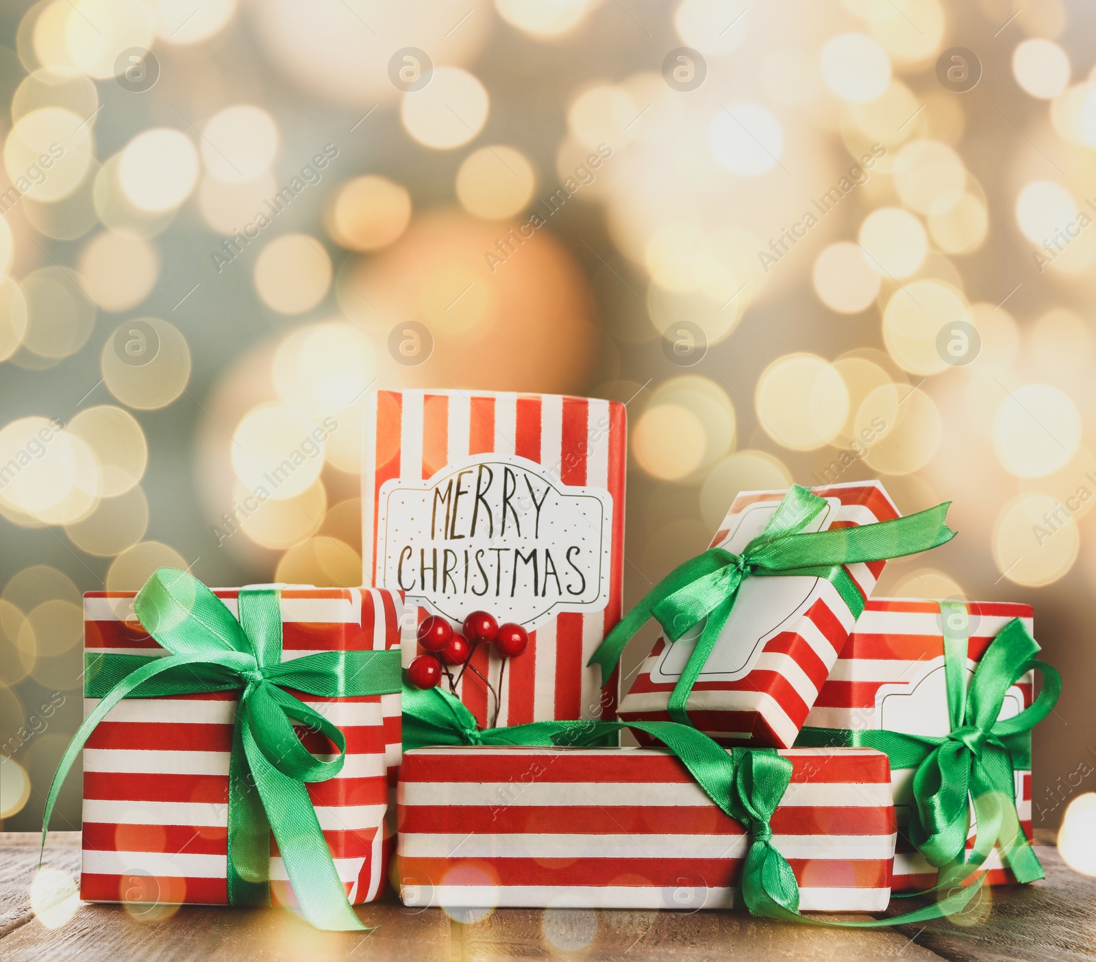 Image of Christmas gift boxes on wooden table against blurred background, bokeh effect