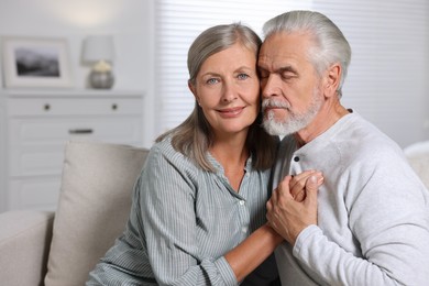 Portrait of affectionate senior couple at home, space for text