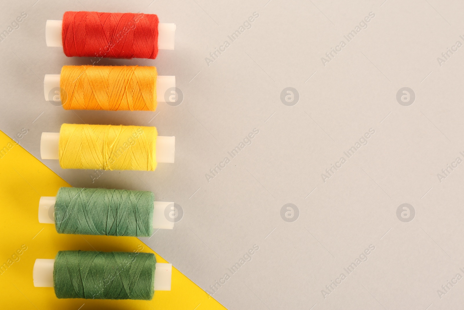 Photo of Different sewing threads on color background, flat lay. Space for text