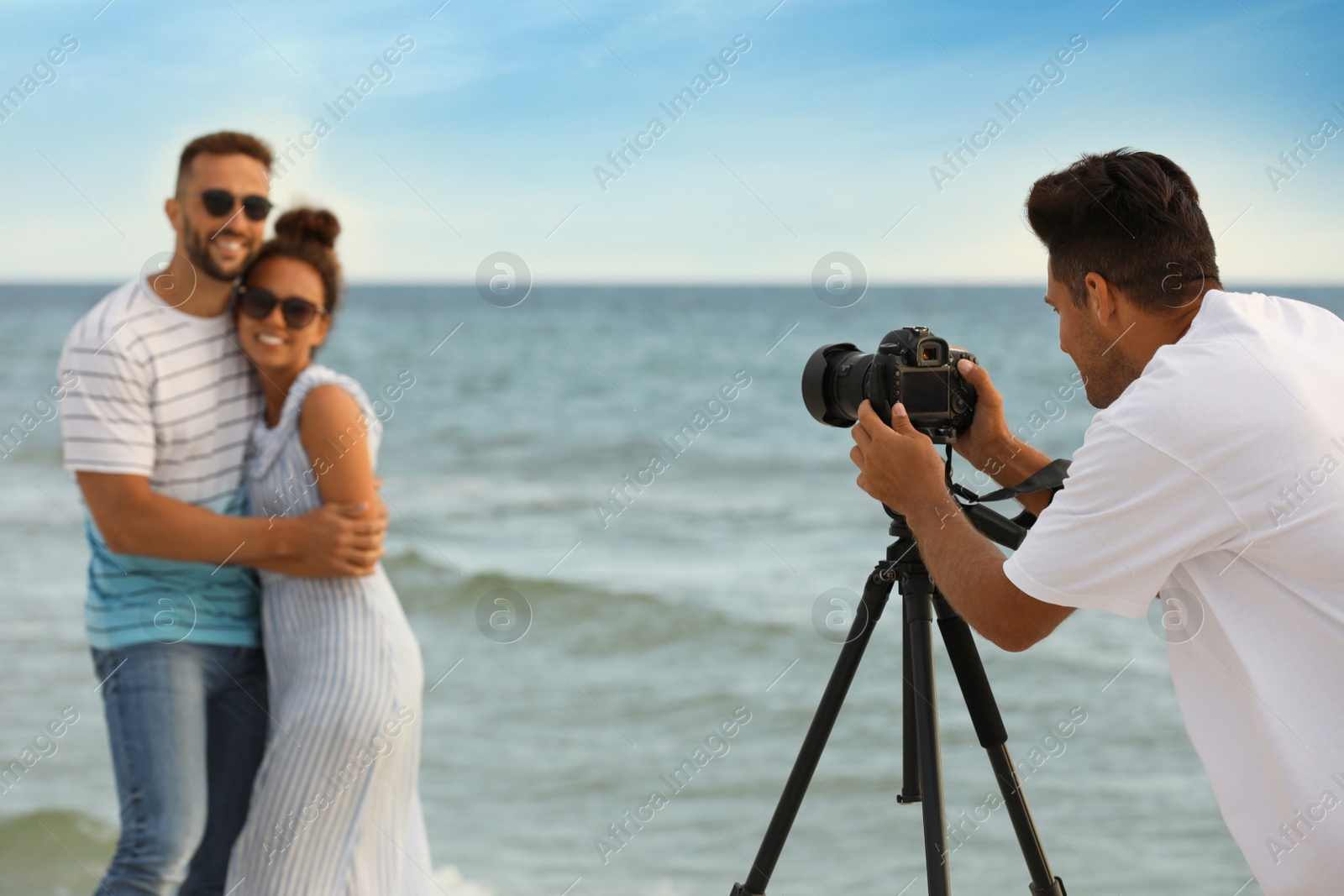 Photo of Photographer taking picture of couple with professional camera near sea