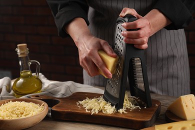 Woman grating cheese at wooden table, closeup