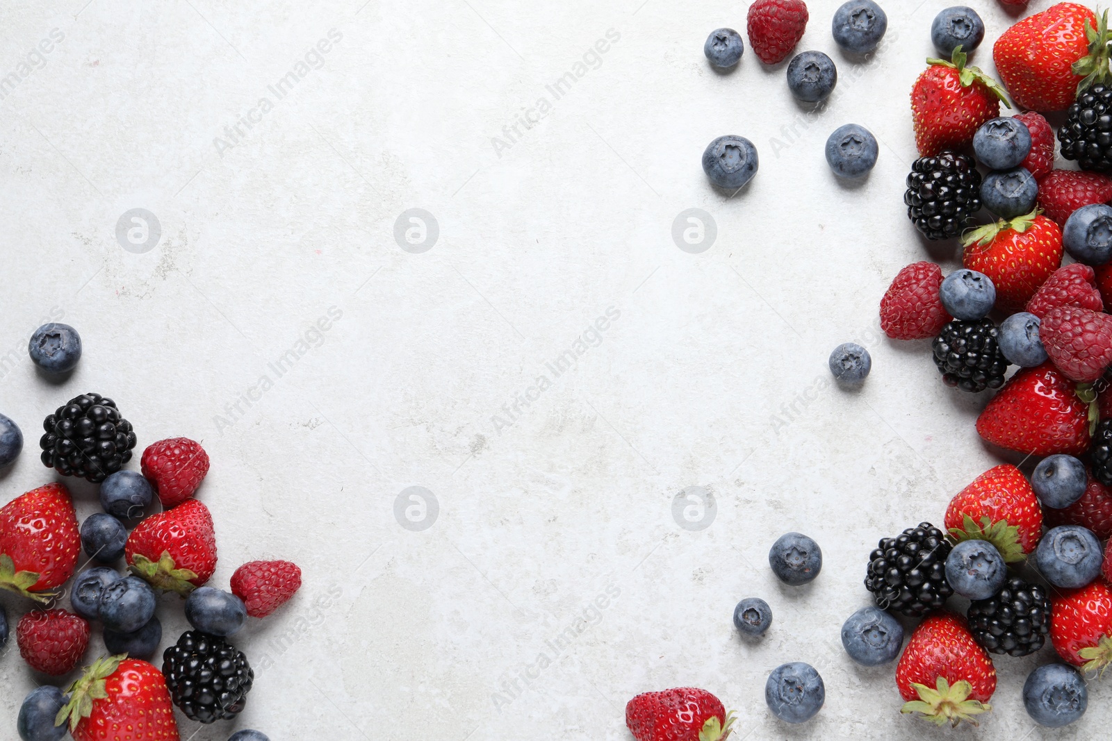 Photo of Many different fresh ripe berries on white textured table, flat lay. Space for text