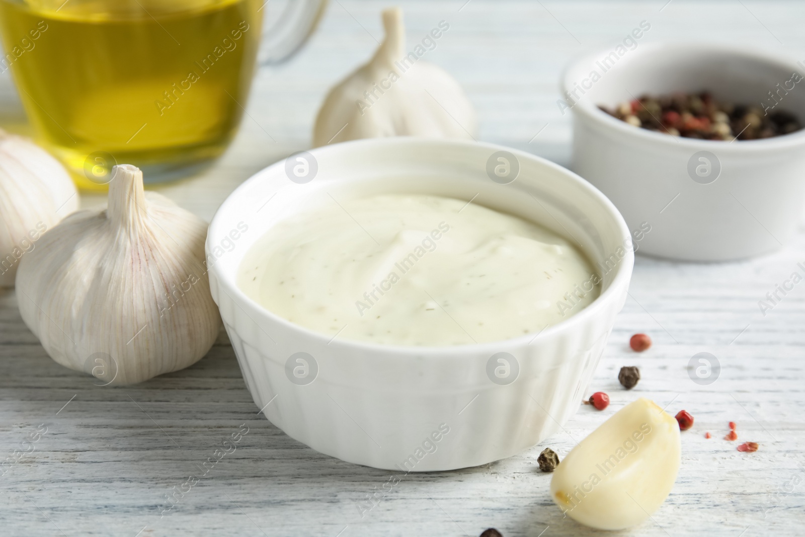 Photo of Fresh garlic and bowl of sauce on white wooden table