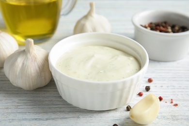 Photo of Fresh garlic and bowl of sauce on white wooden table