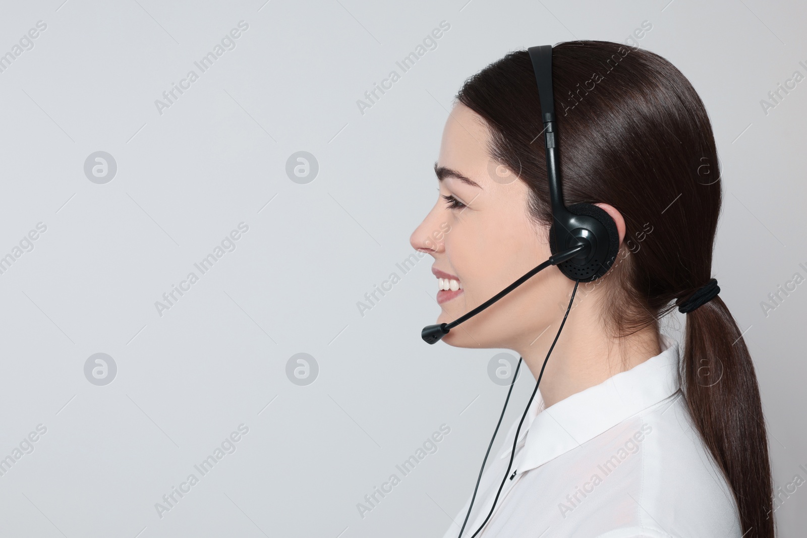 Photo of Hotline operator with modern headset on light grey background, space for text. Customer support