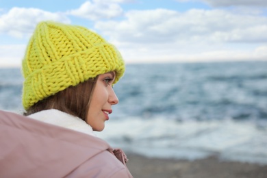 Young woman in warm clothes time near sea