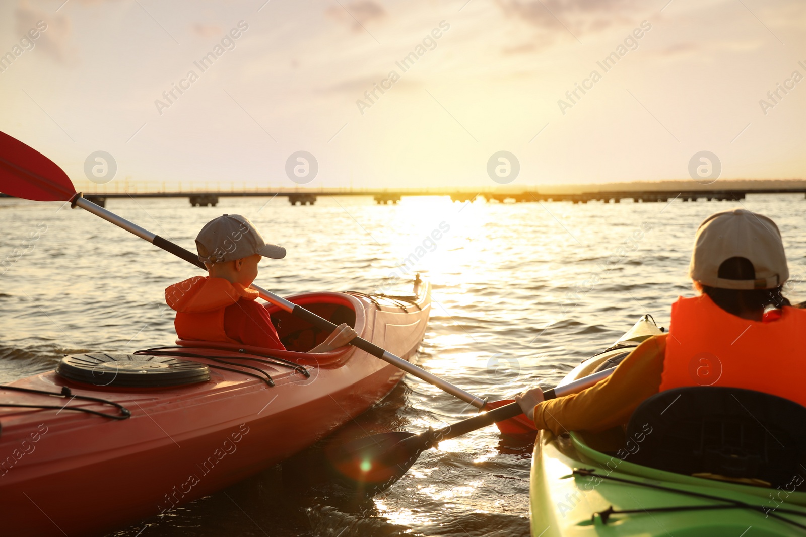 Photo of Little children kayaking on river, back view. Summer camp activity