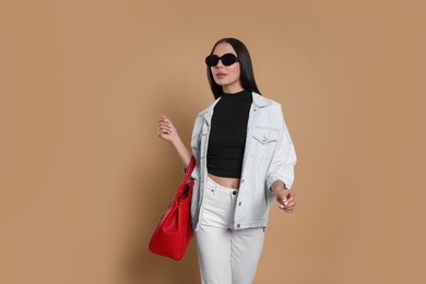 Photo of Young woman with stylish bag on beige background