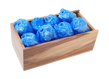 Photo of Rolled blue shoe covers in wooden crate isolated on white