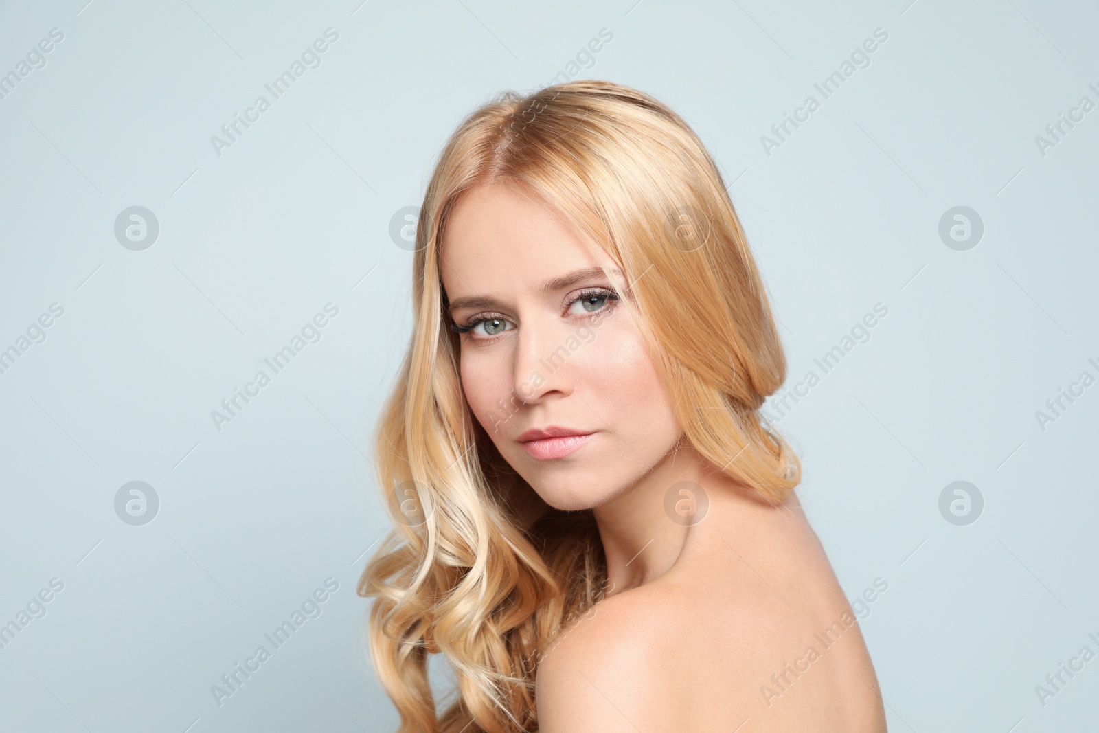 Photo of Beautiful woman with healthy long blonde hair on light background