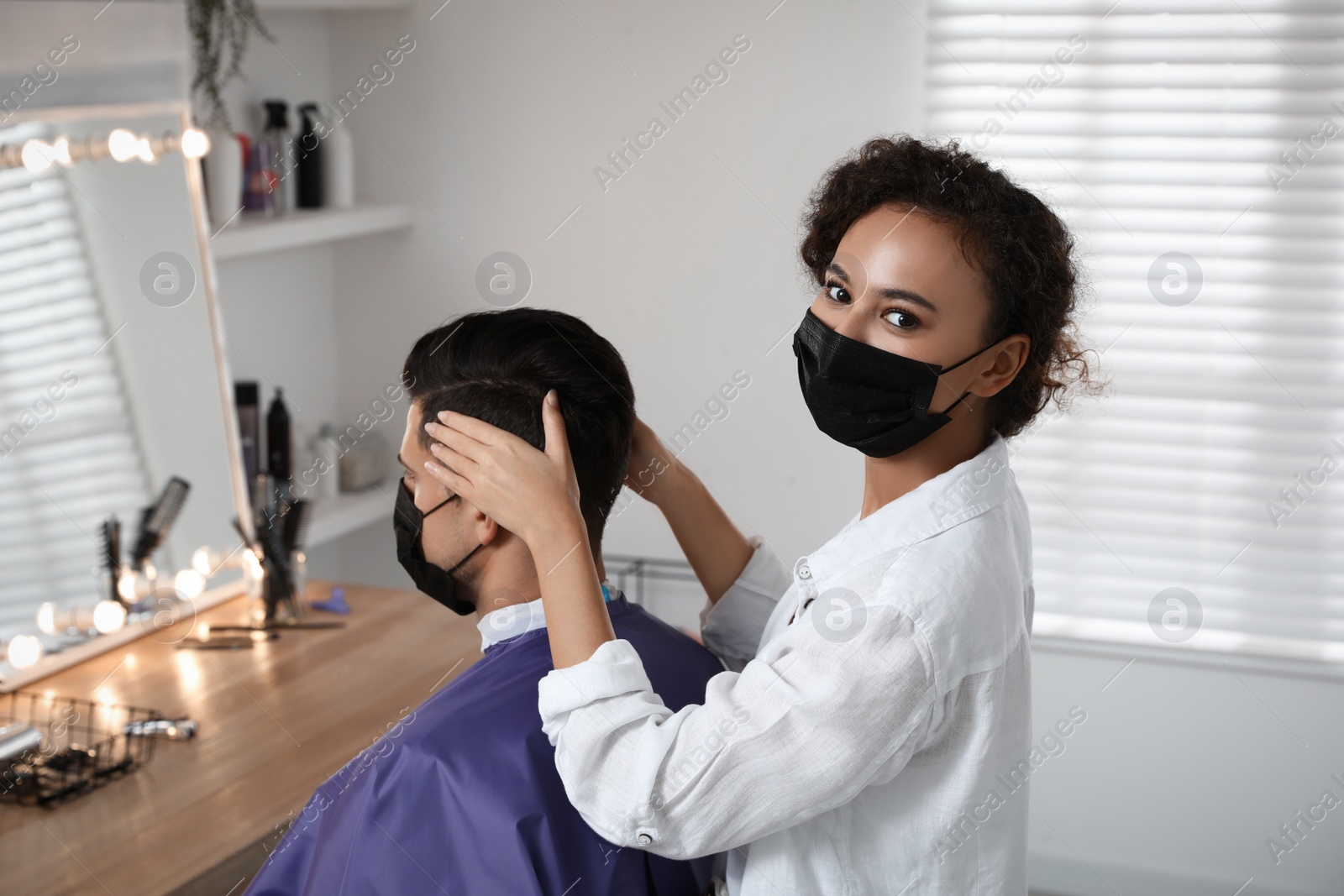 Photo of Professional stylist working with client in salon. Hairdressing services during Coronavirus quarantine