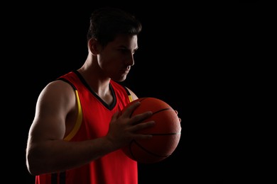 Basketball player with ball on black background