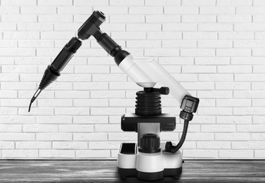 Image of Modern electronic laboratory robot manipulator on wooden table indoors. Machine learning