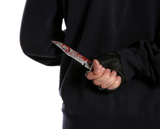 Photo of Man with bloody knife behind his back on white background, closeup. Dangerous criminal