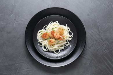 Photo of Delicious scallop pasta with green onion on grey table, top view