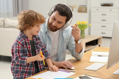 Photo of Man working remotely at home. Father talking with his son at desk