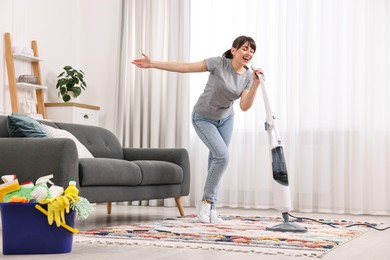 Photo of Happy young housewife having fun while cleaning at home