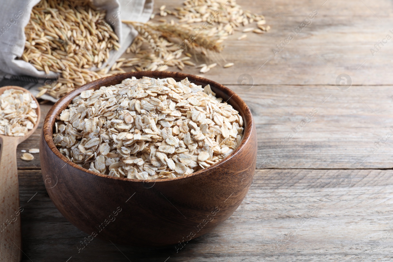 Photo of Bowl with raw oatmeal on wooden table. Space for text