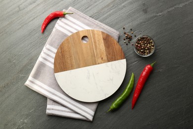 Photo of Cutting board, spices and kitchen towel on dark grey table, flat lay