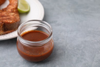 Fresh marinade and cooked fish on grey table, closeup. Space for text