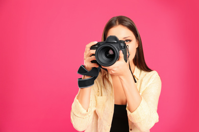 Photo of Professional photographer working on pink background in studio. Space for text