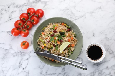 Tasty fried rice with vegetables served on white marble table, flat lay