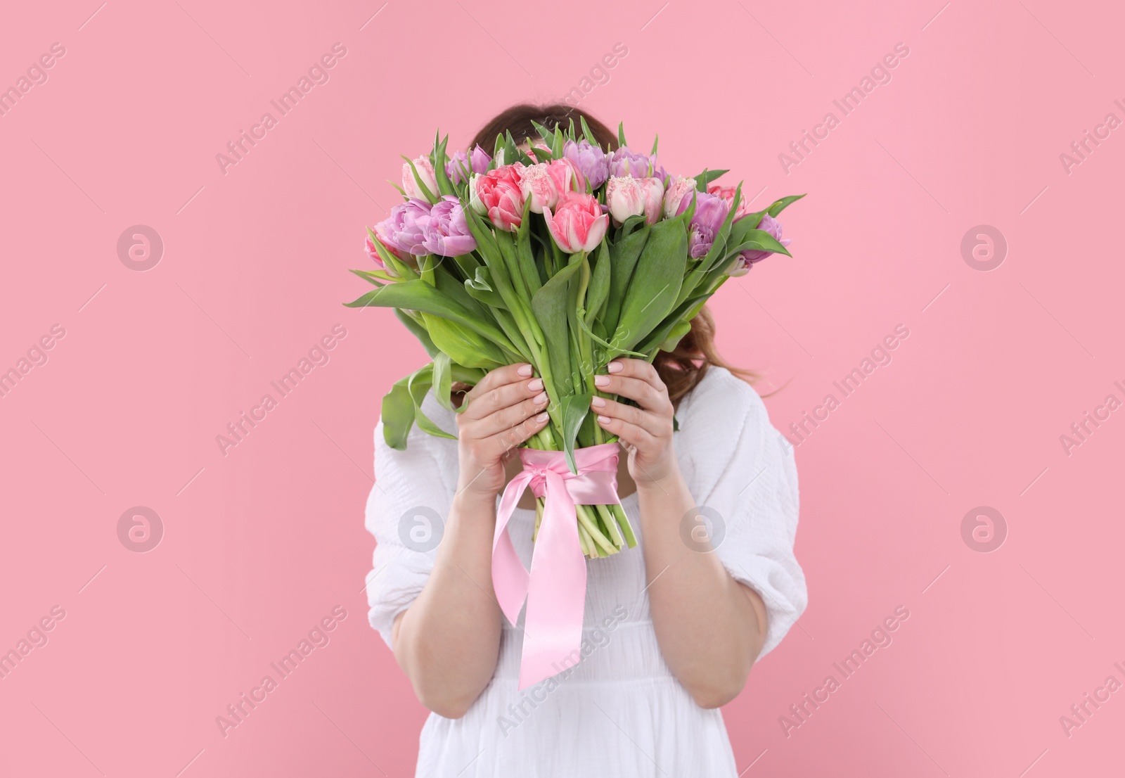 Photo of Young woman holding bouquet of beautiful tulips on pink background