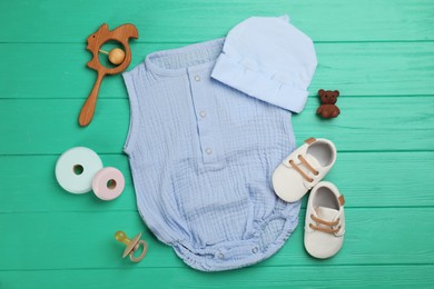 Flat lay composition with baby clothes and accessories on green wooden table