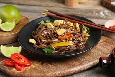 Photo of Stir-fry. Tasty noodles with vegetables and meat served on wooden table