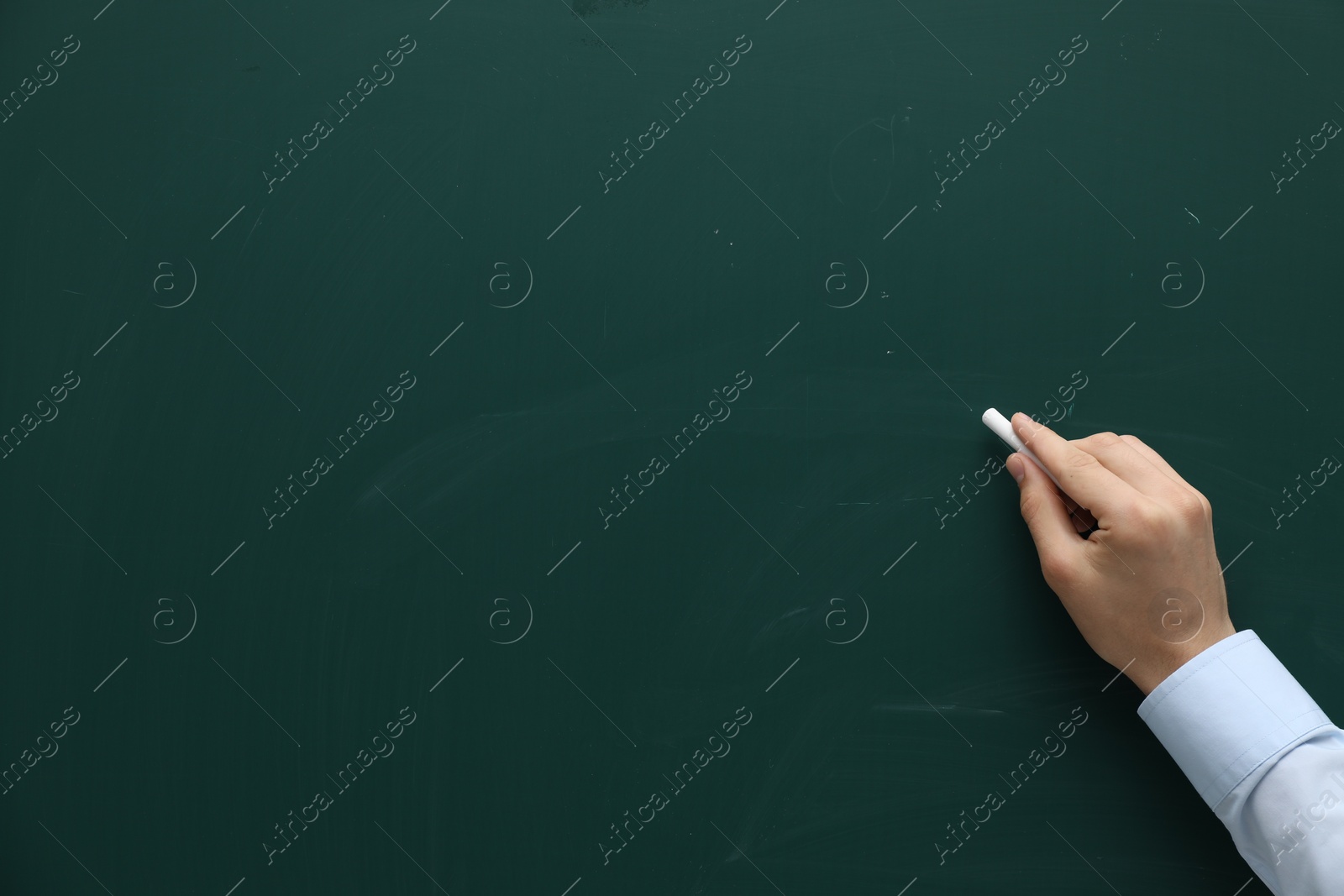 Photo of Teacher writing with chalk on green chalkboard, closeup. Space for text