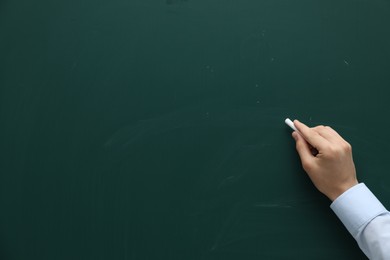 Teacher writing with chalk on green chalkboard, closeup. Space for text