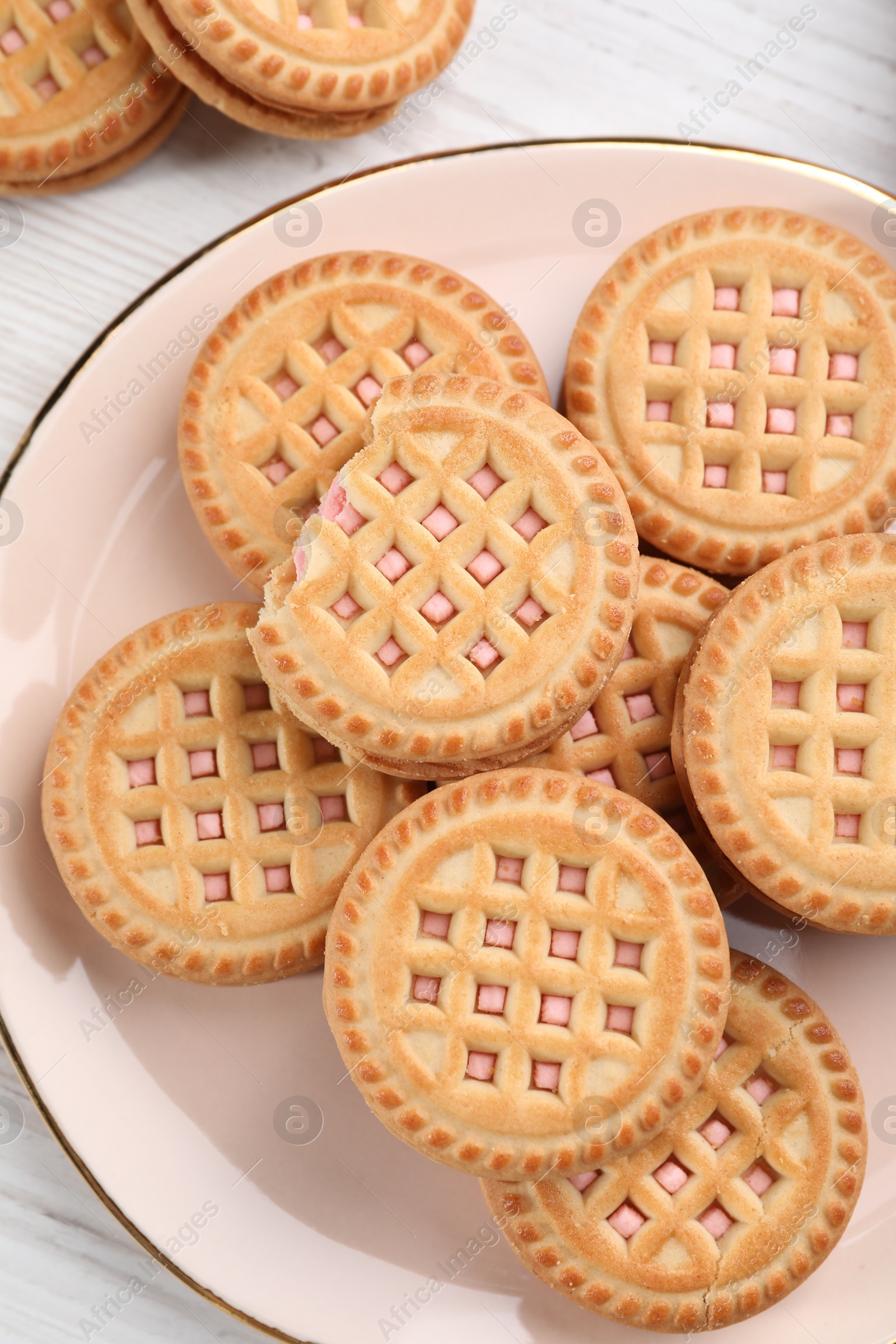 Photo of Tasty sandwich cookies with cream on white wooden table, top view