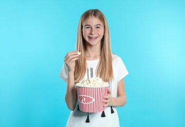 Photo of Teenage girl with popcorn during cinema show on color background