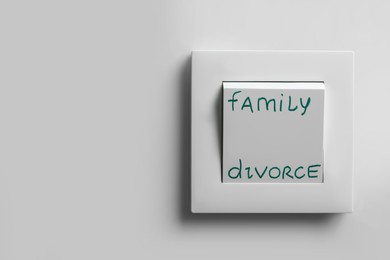 Photo of Light switch with words Family and Divorce on white wall, space for text