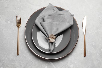 Photo of Plates with fabric napkin, decorative ring and cutlery on light gray marble table, flat lay