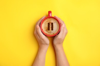 Image of Coffee Break. Woman with cup of americano on yellow background, top view