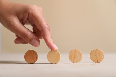 Photo of Choice concept. Woman choosing wooden circle among others at light table, closeup