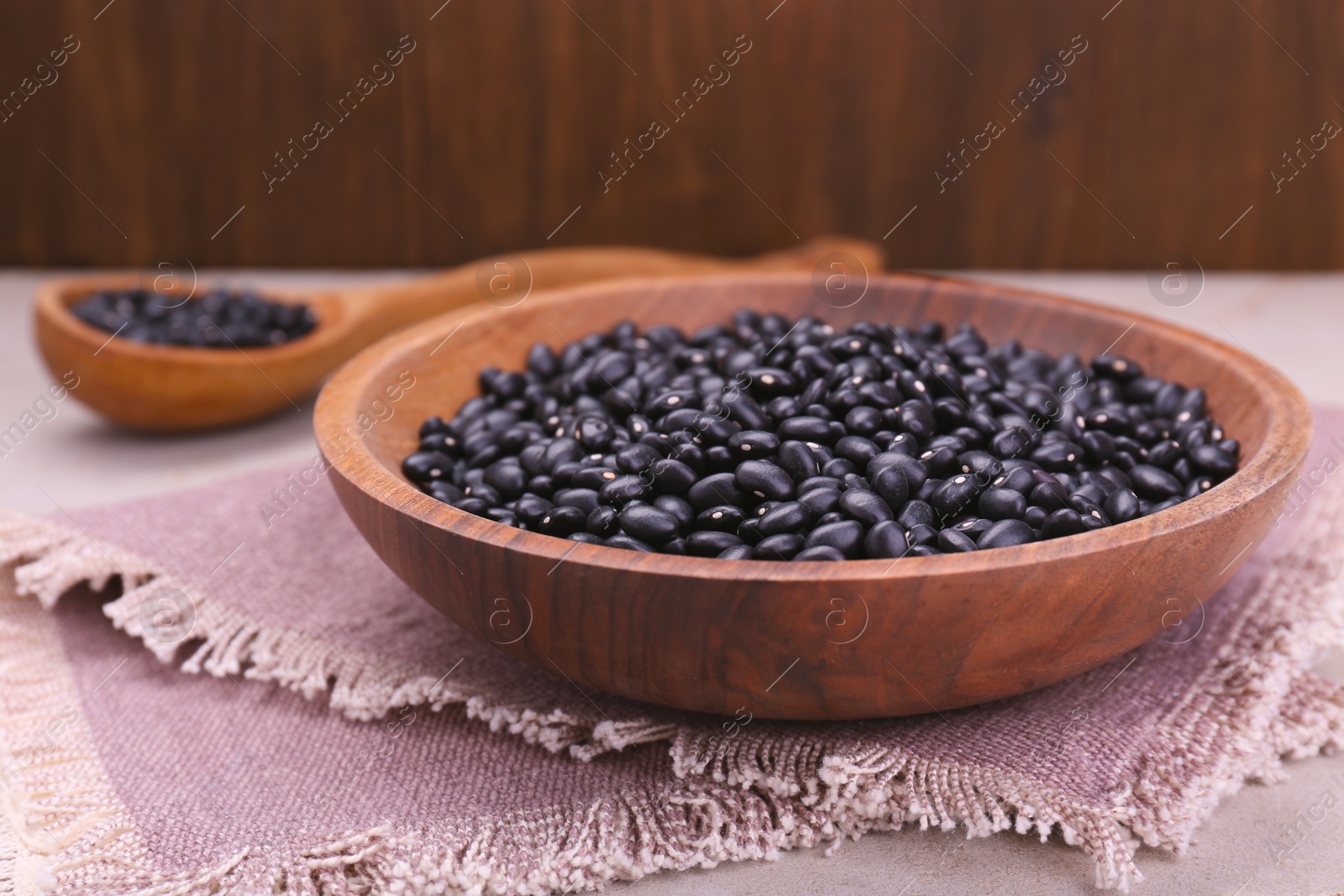 Photo of Bowl of raw black beans on table, closeup