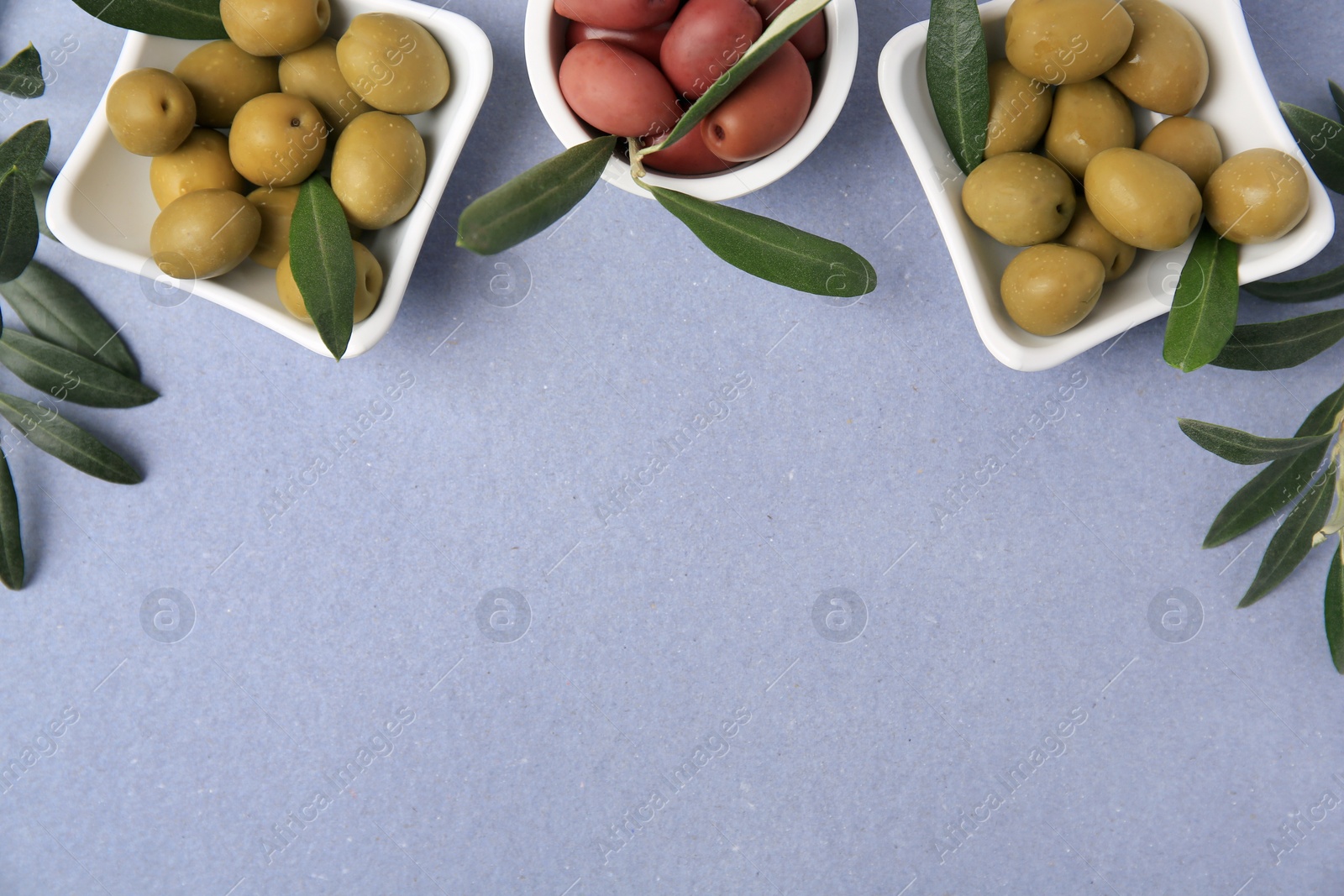 Photo of Different fresh olives and leaves on violet background, flat lay. Space for text