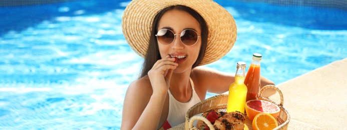 Young woman with delicious breakfast in swimming pool, banner design