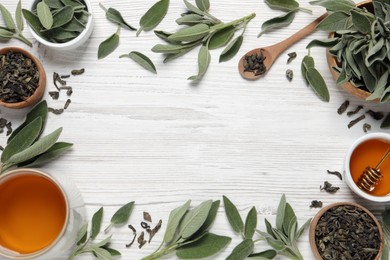 Flat lay composition with cup of sage tea and green leaves on white wooden table. Space for text