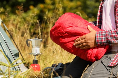 Tourist packing red sleeping bag outdoors, closeup