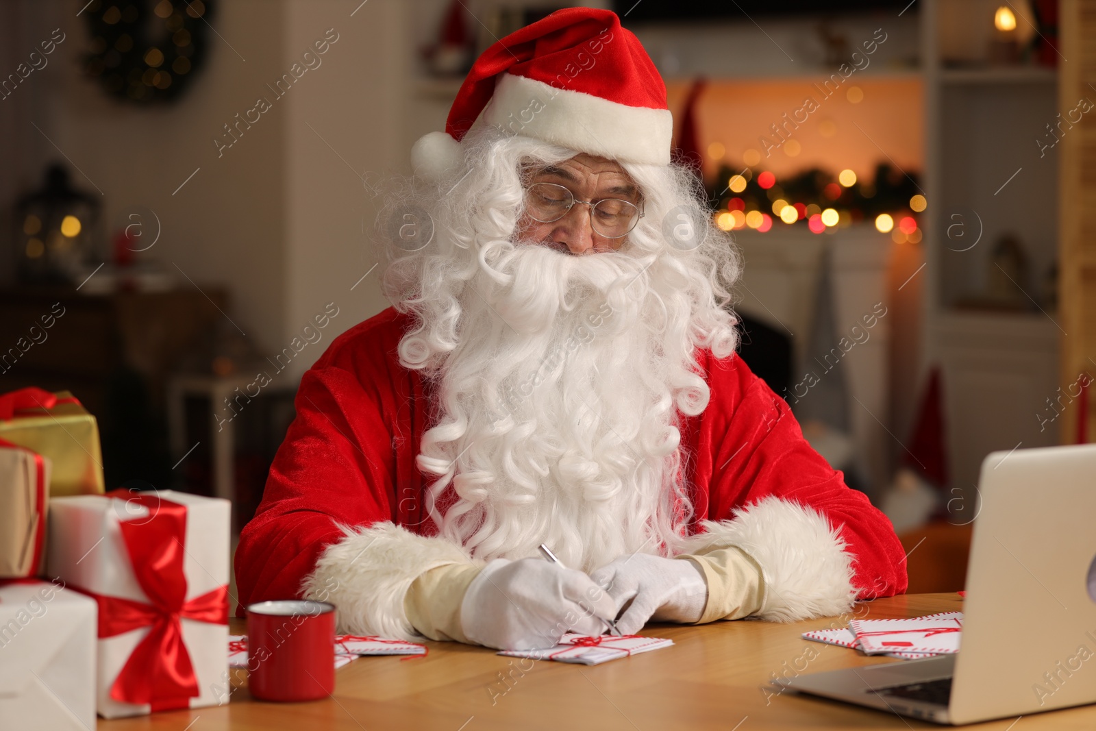 Photo of Santa Claus signing Christmas letters at table in room