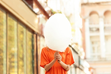 Young woman with cotton candy on city street