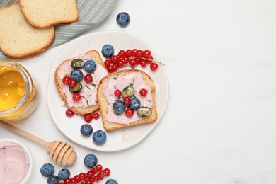 Photo of Tasty sandwiches with cream cheese, berries and honey on white table, flat lay. Space for text