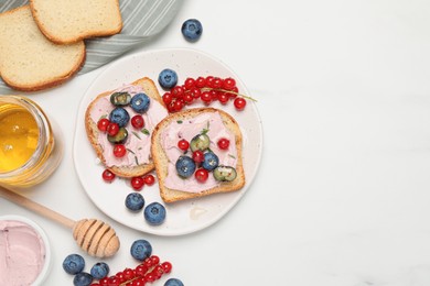 Tasty sandwiches with cream cheese, berries and honey on white table, flat lay. Space for text