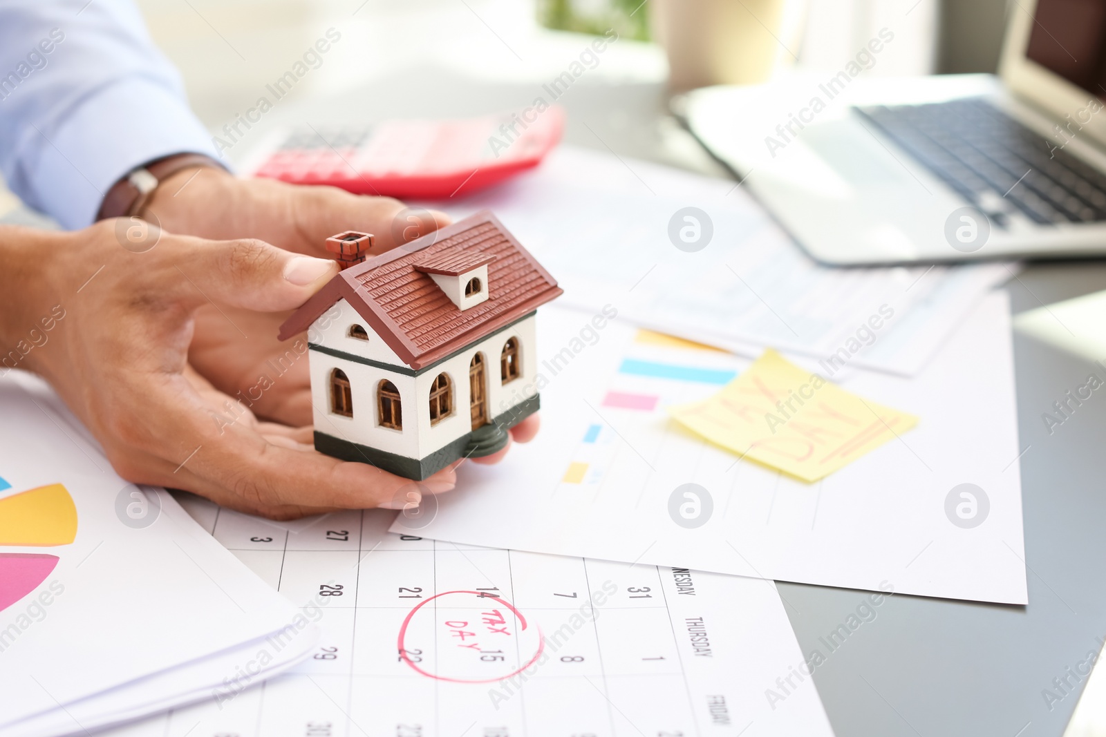 Photo of Man holding house model at table, closeup. Property tax