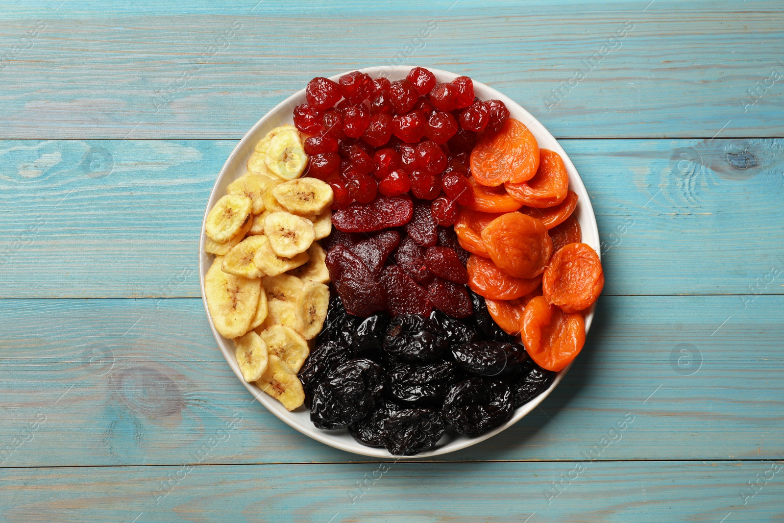 Photo of Delicious dried fruits on light blue wooden table, top view